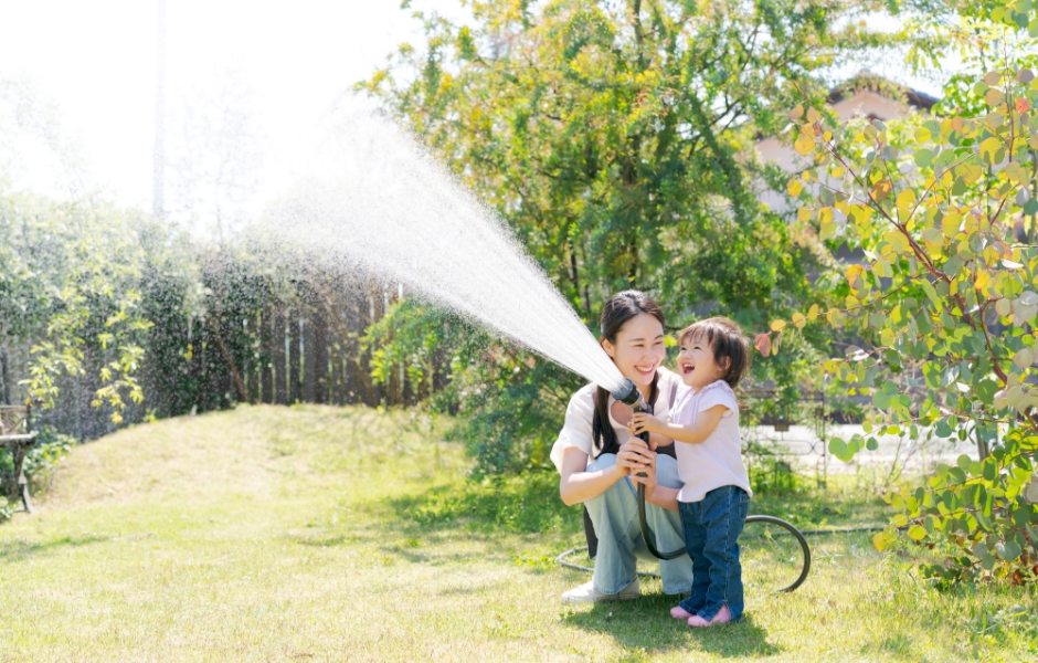 庭で水やりをする母親と子ども イメージ写真